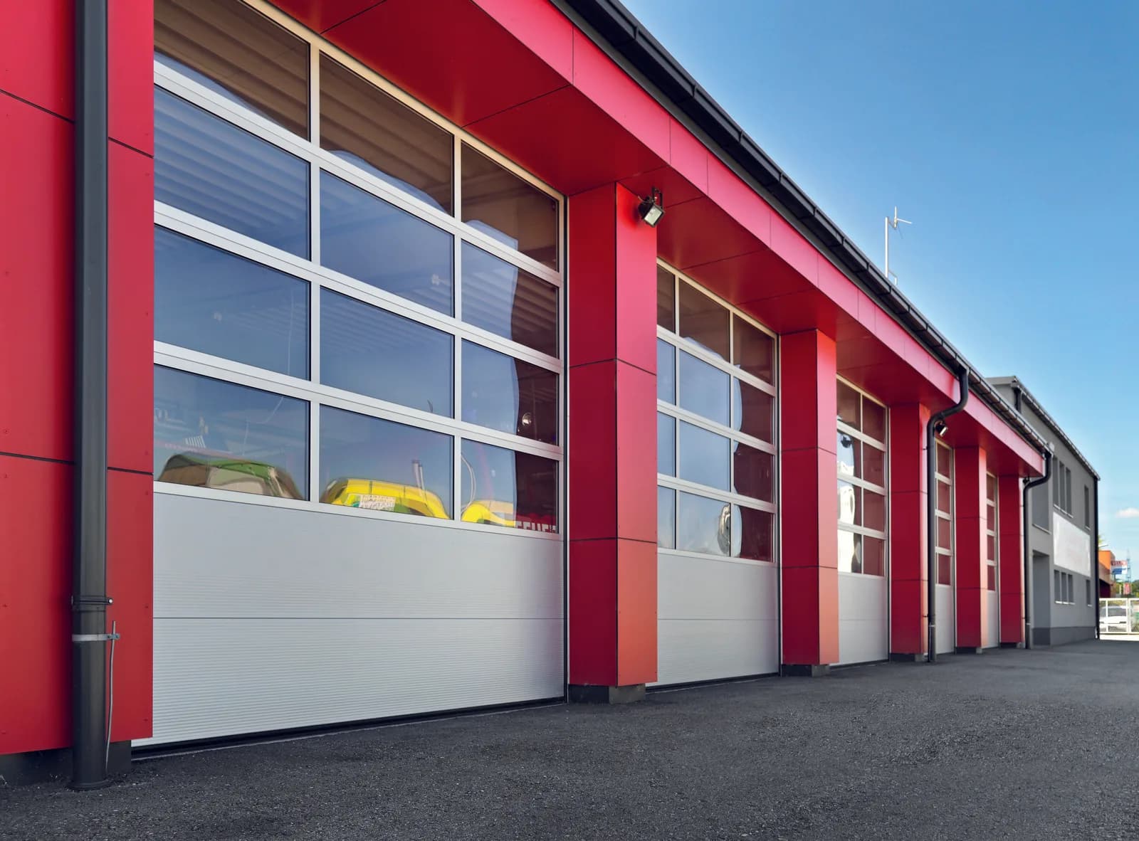 Verglaste ALU40-Sektionaltore an einer Fahrzeughalle mit roter Fassade