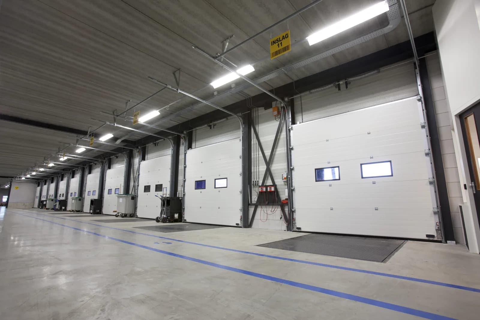 Innenansicht einer Logistikhalle mit mehreren weißen ISO60-Sektionaltoren an Verladerampen